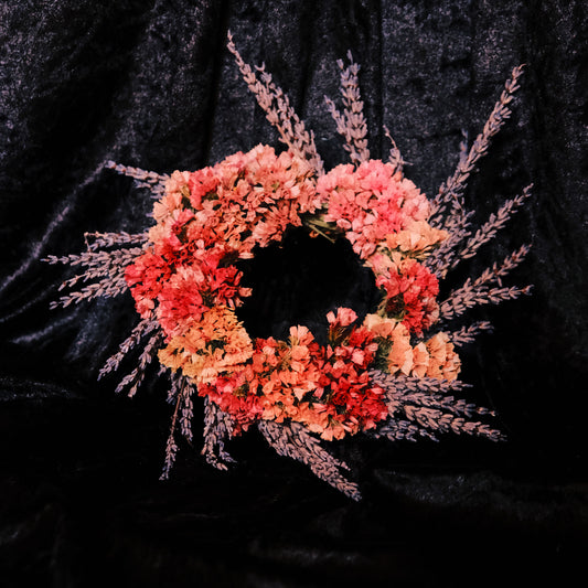 Floral wreath with pink and orange flowers on a black background. Lavender and statice floral wreath.