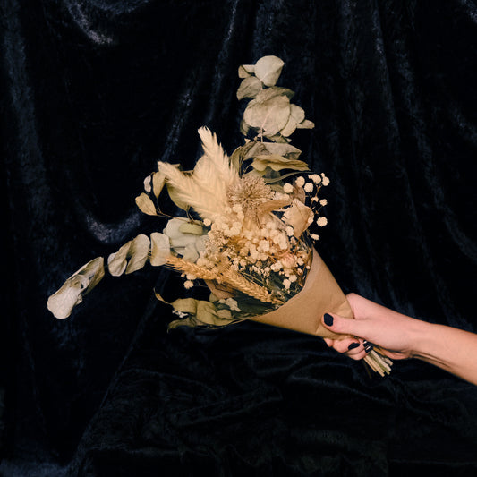 Bouquet of dried flowers held by a hand against a black background