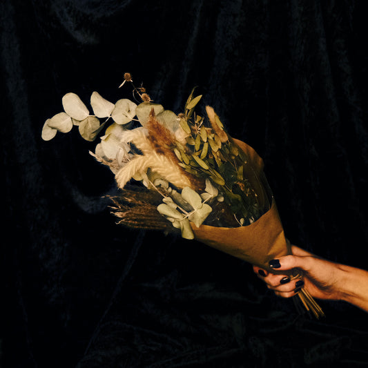Hand holding a bouquet of dried flowers against a dark background