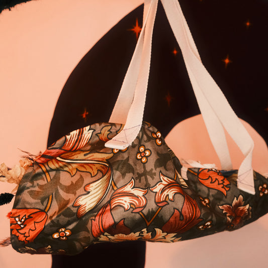 Decorative floral bouquet bag with floral patterns and ribbons against a celestial background