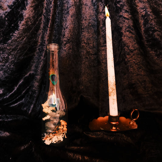 Candle and bottle with flowers against a dark textured background