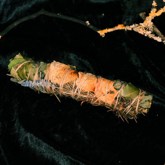 Cleansing wand made of homegrown herbs on a dark background featuring  a stick covered in lichen 