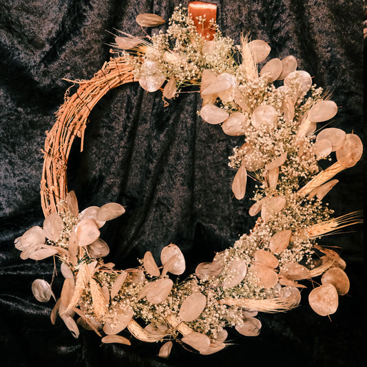 Decorative wreath with home grown and dried neutral tone flowers and on a dark velvet background